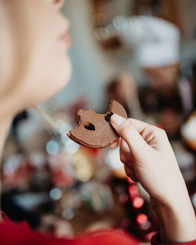 A close-up of a hand holding a bitten chocolate biscuit