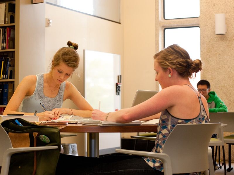 Two students working at a table in a bright modern library