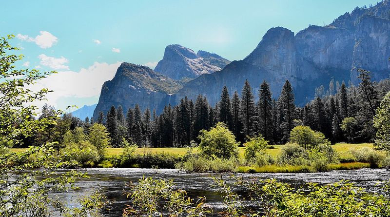 A river in front of granite cliffs and pine forest
